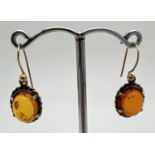 A pair of yellow metal amber set drop style earrings. Oval cut amber cabochon in a rope detail