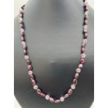 A 20 inch garnet and clear bead necklace with white metal push clasp.