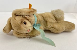 A vintage Steiff reclining rabbit plush toy with blue ribbon necktie and buttoned ear. Approx. 12"