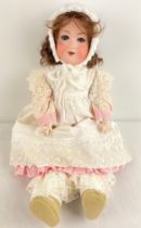 An antique 22" Armand Marseille 390 doll with bisque head and jointed composite body. Closing blue