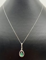 An oval shaped silver, emerald and diamond pendant on an 18" curb chain with spring ring clasp.