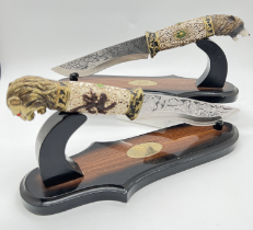 2 ornamental collectors knives complete with display stands. One with wolf head handle, engraved