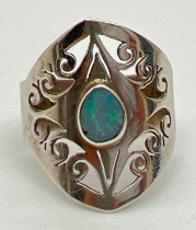 A modern design silver dress ring with pierced work scroll detail and a central bezel set opal.