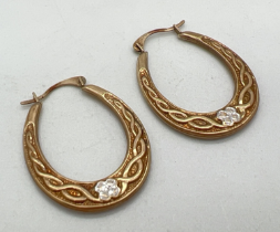 A pair of 9ct gold hoop style earrings with Celtic design and white gold floral accent. Gold Mark to
