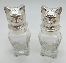 A glass salt & pepper cruet with silver plated tops modelled as cats heads. Each approx. 11.5cm