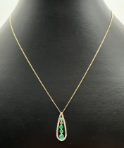 A teardrop shaped emerald and diamond pendant with 5 graduating emeralds haloed with 4 illusion