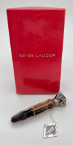 A boxed Estee Lauder vial shaped perfume bottle with pierced work white metal lid with floral