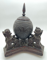 A vintage highly carved coconut shell canister raised on a carved wooden tripod stand with Foo dog