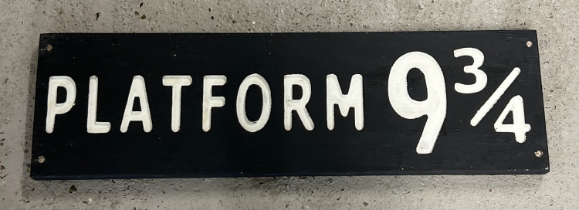 A modern painted wood Harry Potter Platform 9Â¾ sign, in black & white. Approx. 59cm long.