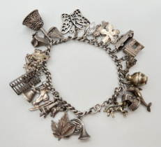 A vintage white metal charm bracelet with 26 assorted silver & white metal charms. Charms to include