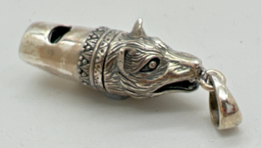 A silver whistle modelled as a wolfs head, with hanging bale. Marked sterling to underside.