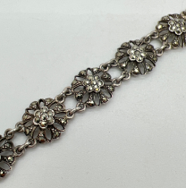 A vintage silver floral link bracelet with 10 pierced work links set with marcasite stones. Push