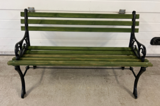 A green painted wooden slatted garden bench with cast iron bench ends with scroll detail. Approx.