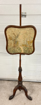 A Victorian mahogany pole screen with needlepoint panel depicting a wooded scene with flowers.