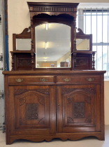 An Edwardian dark oak mirror backed side board with decorative carved columns and panelled detail.