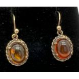 A pair of unmarked gold drop earrings set with cabochons of amber with rope detail to mounts. Test