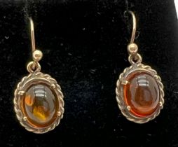 A pair of unmarked gold drop earrings set with cabochons of amber with rope detail to mounts. Test