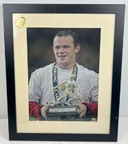 A framed and glazed signed photograph of Manchester United footballer Wayne Rooney. Complete with