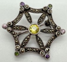 A vintage silver brooch modelled as a star/spiders web, set with round cut coloured stones and