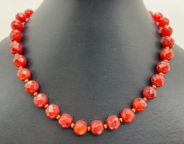 A 15" necklace of 1cm diameter faceted Carnelian beads with gold tone spacer beads and fishhook