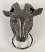 A cast iron wall hanging ornament modelled of a rams head with a ring. With fixing holes to reverse.