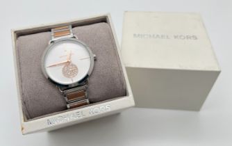 A boxed ex shop stock ladies wristwatch by Michael Kors. Rose gold and silver tone stainless steel