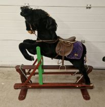 A vintage rocking horse on a trestle base, with uprights formed as a show jumping fence. With purple