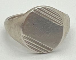 A vintage silver oval shaped signet ring with engraved channelled design and empty cartouche.