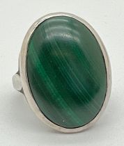 A white metal dress ring set with large oval cabochon of malachite. Ring size P. Stone size