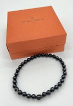 A new in box black onyx circular and skull bead expanding bracelet by Simon Carter, London.