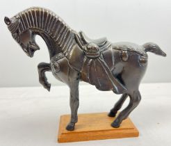 A heavy cast metal figurine of an Indian ceremonial horse on a wooden plinth base. Approx. 20cm