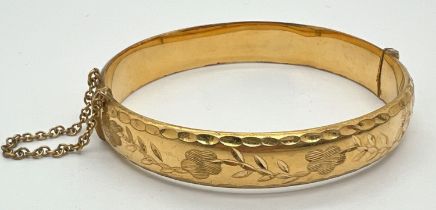 A vintage 9ct rolled gold bangle with safety chain and half floral engraved decoration. Marks to