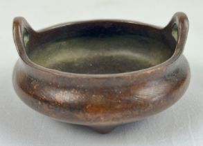 A small Chinese bronze censer with loop handles and raised on tripod feet. Impressed mark to