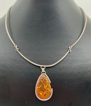 A white metal modernist design hinged torque style necklace with large amber teardrop pendant and