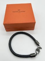 A boxed Simon Carter, London, men's plaited black leather bracelet with black metal lobster clasp,