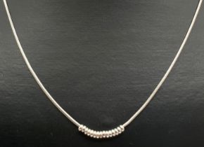 A modern design 18 inch silver snake chain necklace with moving small circular bead decoration.