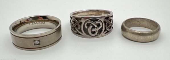 3 band rings. A large silver celtic knot design ring, a titanium band ring set with a small clear