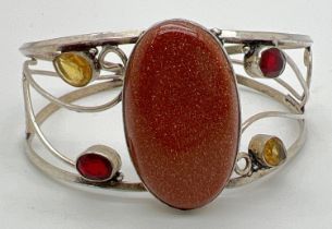 A silver modern design open scroll work cuff bangle set with large central brown sandstone, 2 oval