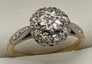 An 18ct gold and platinum diamond cluster ring. Small round cut central diamond surrounded by 8