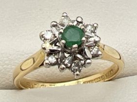 An 18ct gold, emerald and diamond dress ring. High set central round cut emerald surrounded by 6