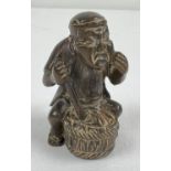 A small carved wood netsuke of an Oriental man stirring a barrel. Set with small mother of pearl