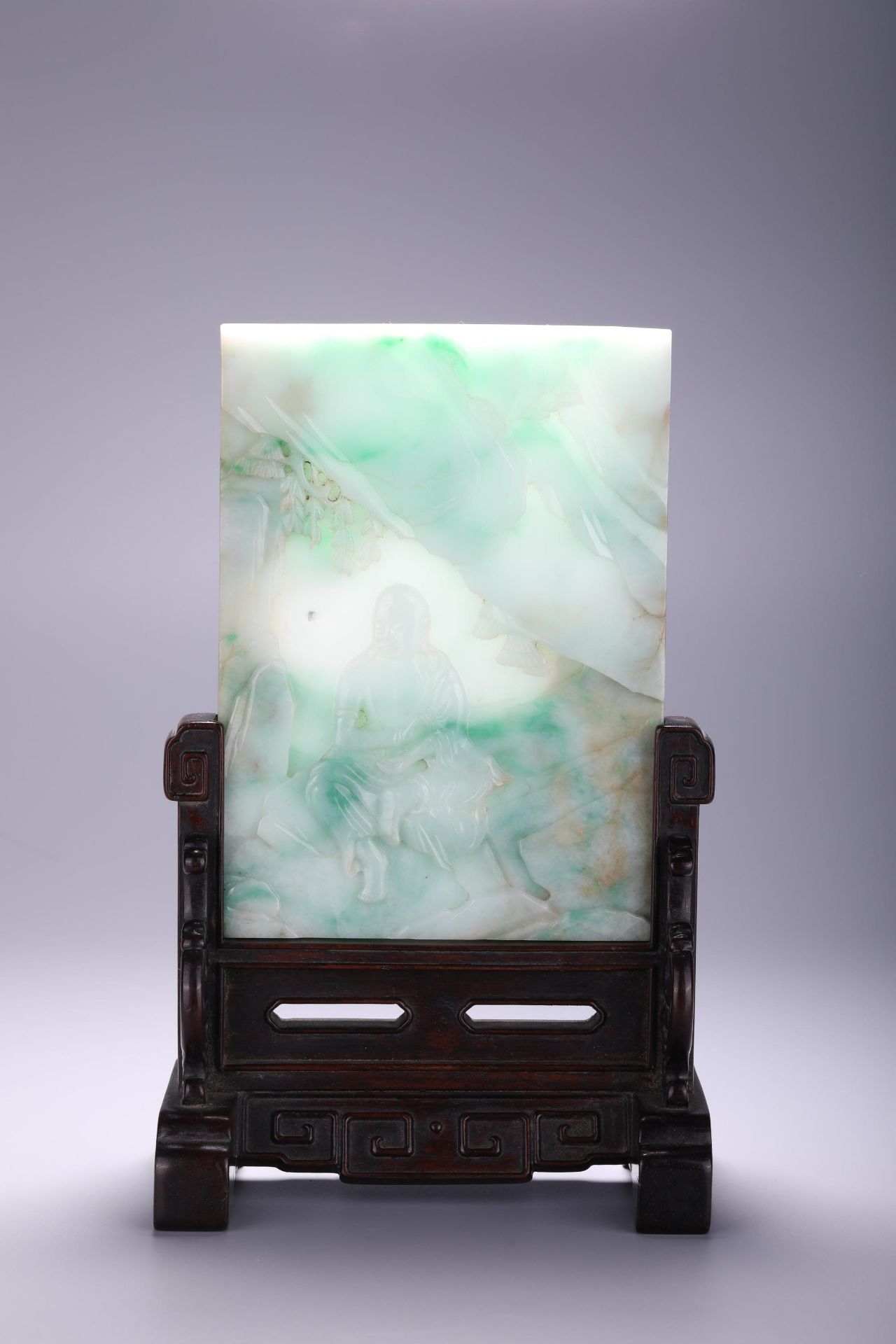 A Chinese carved jadeite feicui jade plaque fitted in a wooden stand, L 16 - W 11,9 - Depth 1 cm