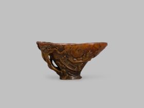 A Finely Carved Rhinoceros Horn Cup, 18th century, depicting a river gorge among mountains, where