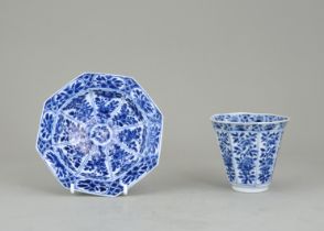 A Blue and White Cup and Saucer, Kangxi, the cup of deep octagonal form with panels of flowering