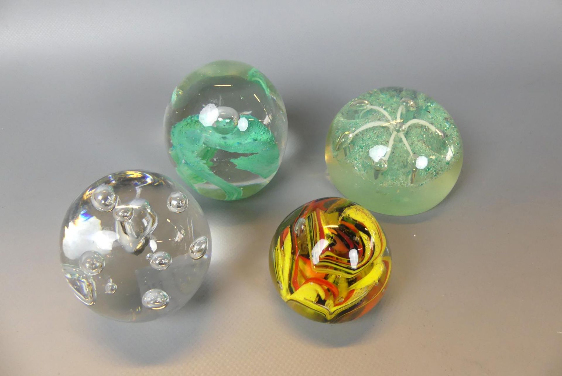 4 Paperweights, farbloses Glas mit reichen farbigen Einschmelzungen