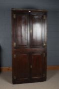 18th century oak panelled corner cupboard, having two pairs of doors, the upper doors enclosing a
