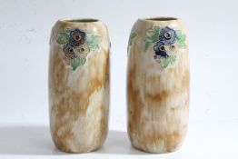 Pair of Royal Doulton stoneware vases, each with tubelined flowers on a brown mottled ground,