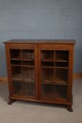 20th century golden oak bookcase, having a pair of glazed doors enclosing two shelves, 106cm wide,