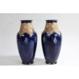 Pair of Royal Doulton stoneware vases, the bulbous vases with roses to the necks on a dark blue