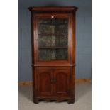 George III oak corner cabinet, having a glazed door opening to reveal three shelves and having a